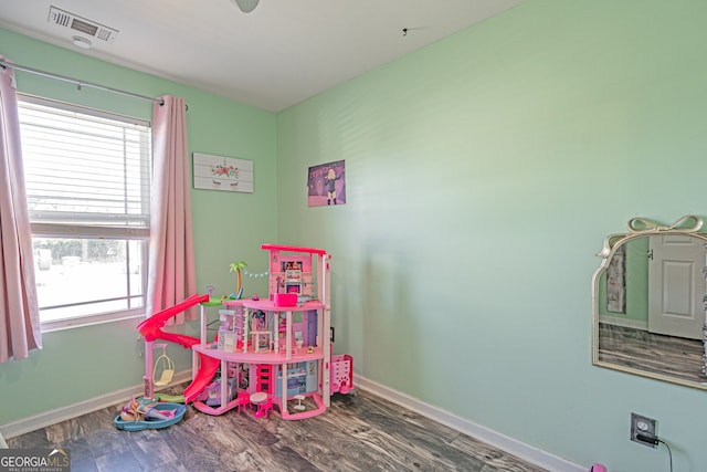 recreation room featuring wood finished floors, visible vents, a wealth of natural light, and baseboards