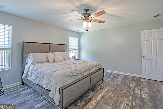 bedroom featuring dark wood finished floors, baseboards, visible vents, and ceiling fan