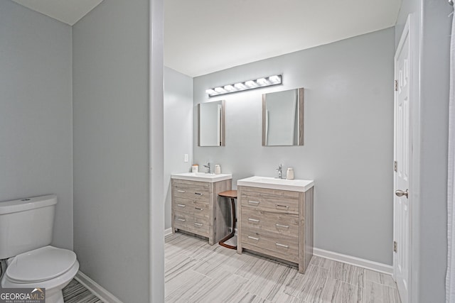 bathroom featuring vanity, toilet, wood finished floors, and baseboards