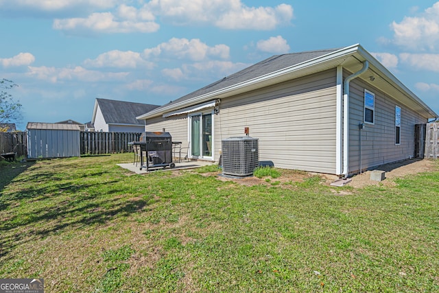 rear view of property with a patio, an outbuilding, central AC, and a fenced backyard