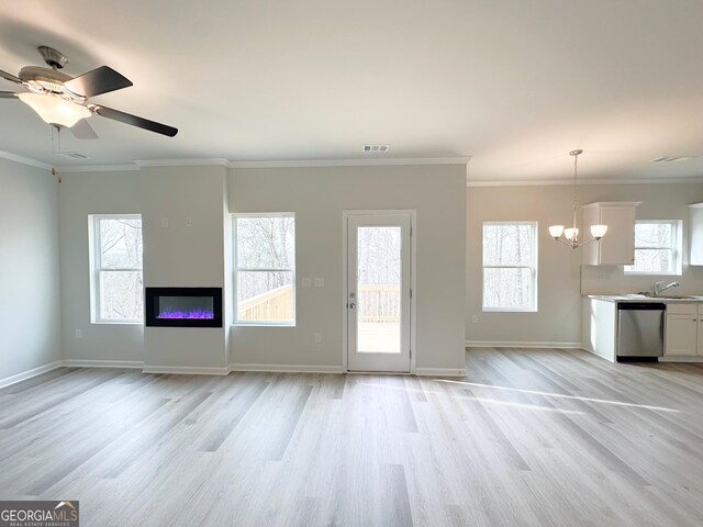 unfurnished living room featuring a wealth of natural light, visible vents, light wood-style flooring, and a sink