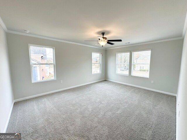 carpeted spare room featuring crown molding, plenty of natural light, and baseboards