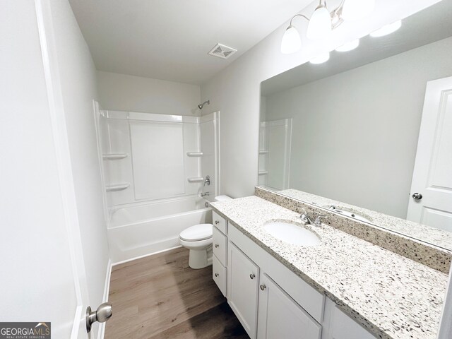 bathroom with visible vents, toilet, shower / bathing tub combination, wood finished floors, and vanity