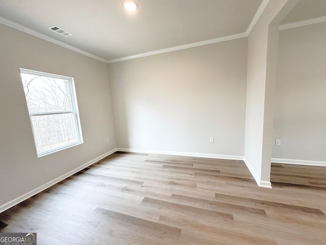 empty room with visible vents, crown molding, baseboards, and wood finished floors