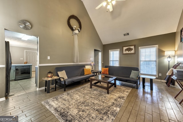 living room with high vaulted ceiling, baseboards, visible vents, and light wood-type flooring