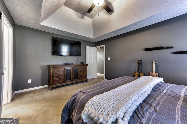 bedroom featuring baseboards, carpet floors, a tray ceiling, ceiling fan, and a textured ceiling