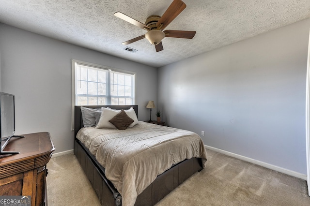 bedroom with visible vents, light carpet, a textured ceiling, baseboards, and ceiling fan