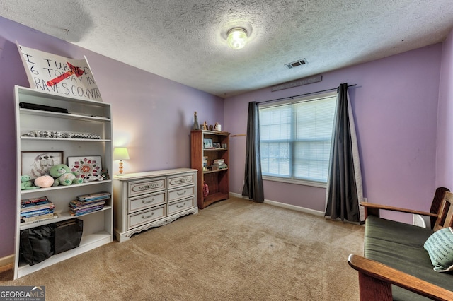 living area with a textured ceiling, carpet, visible vents, and baseboards