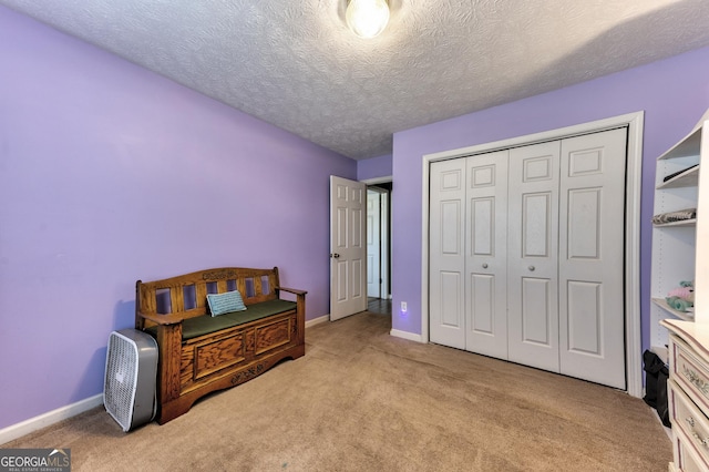 bedroom with a textured ceiling, carpet, a closet, and baseboards