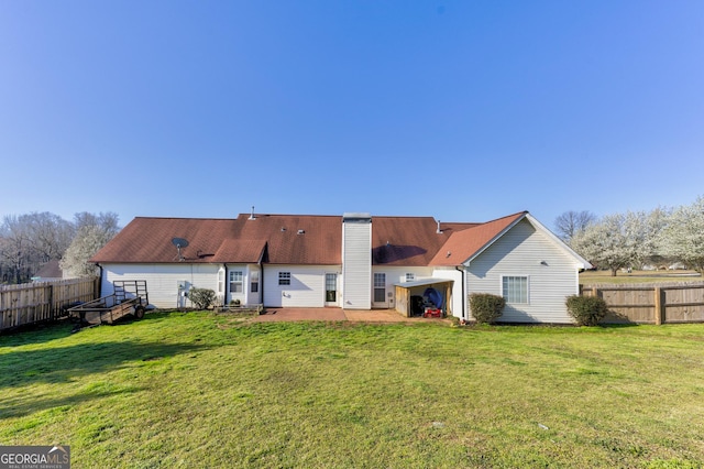 rear view of property with a patio, a yard, a fenced backyard, and a chimney