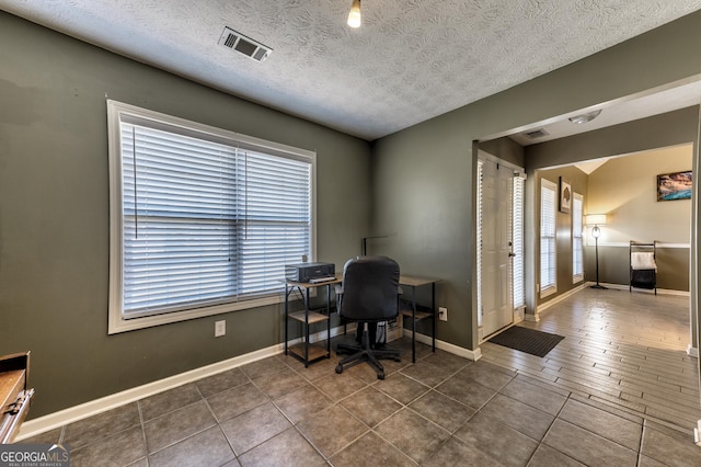 home office with dark tile patterned flooring, baseboards, visible vents, and a textured ceiling