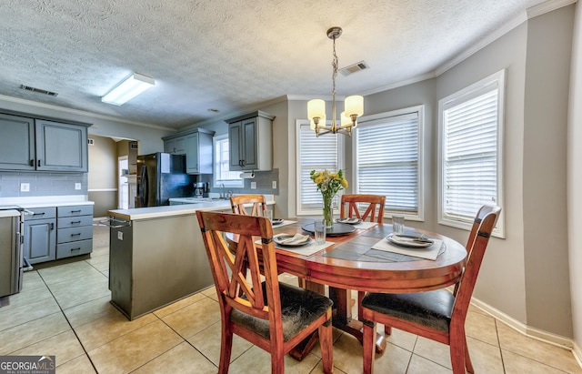 dining space featuring light tile patterned floors, visible vents, crown molding, and a chandelier