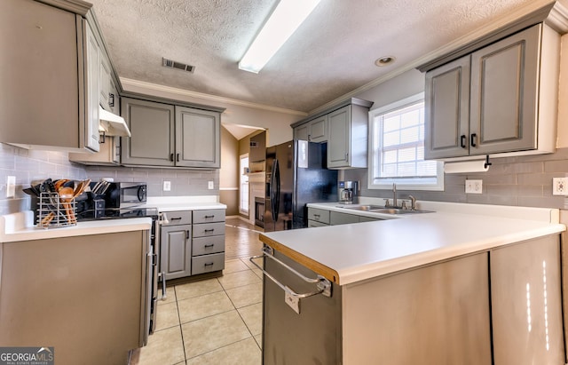 kitchen with under cabinet range hood, gray cabinetry, light tile patterned flooring, and a sink