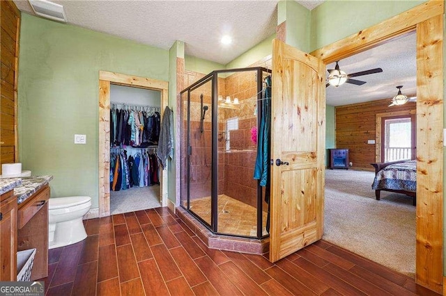 ensuite bathroom featuring a textured ceiling, a shower stall, ensuite bath, and wood tiled floor