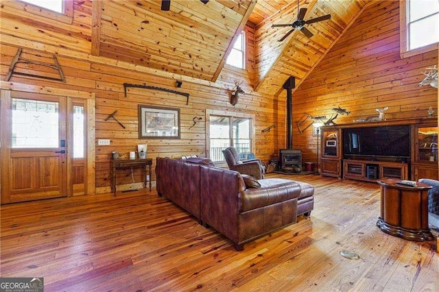 living room featuring wood walls, wood ceiling, a wood stove, and hardwood / wood-style floors