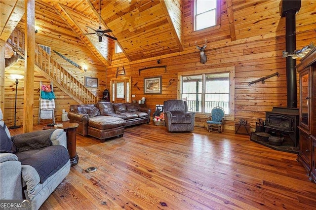 living area with stairway, a wood stove, wood walls, and wood-type flooring