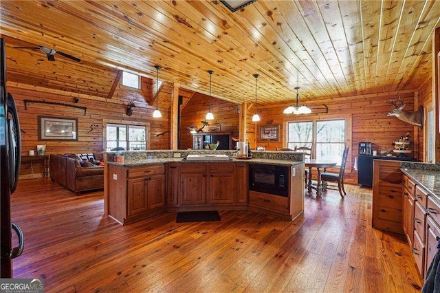 kitchen featuring hardwood / wood-style floors, a healthy amount of sunlight, open floor plan, and black microwave