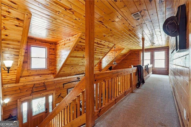 corridor with visible vents, carpet, wooden ceiling, wood walls, and lofted ceiling