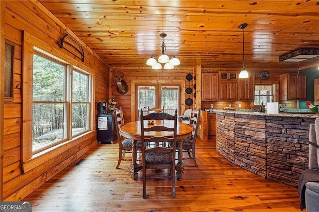 dining room featuring wooden ceiling, wooden walls, light wood finished floors, and a chandelier