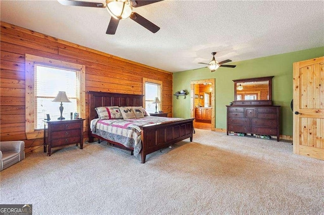 carpeted bedroom with ceiling fan, a textured ceiling, and wood walls