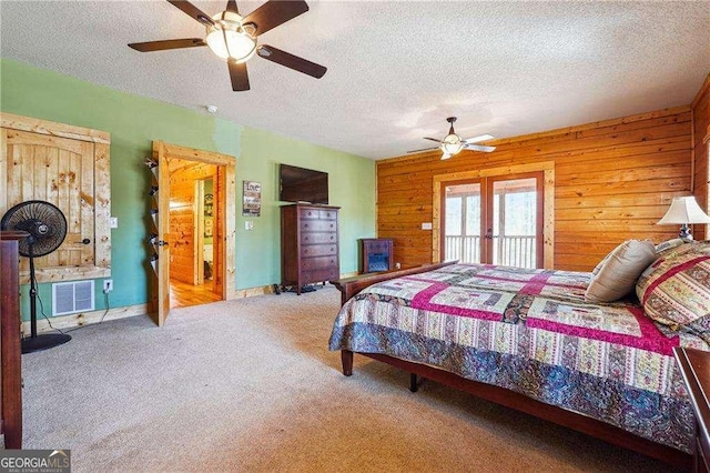 bedroom featuring visible vents, wood walls, carpet floors, and a textured ceiling