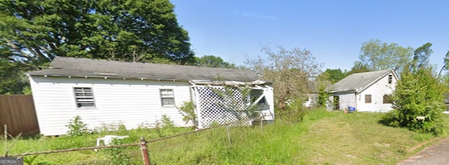 view of side of home with an outbuilding and fence