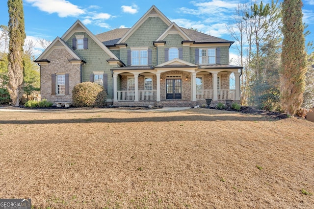 craftsman house with brick siding, a porch, and a front yard