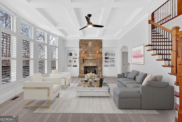 living room with visible vents, built in features, a fireplace, coffered ceiling, and a ceiling fan