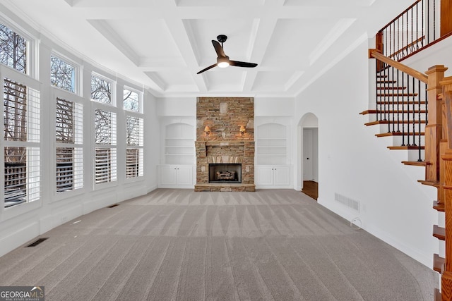 unfurnished living room featuring a stone fireplace, built in features, visible vents, and carpet floors