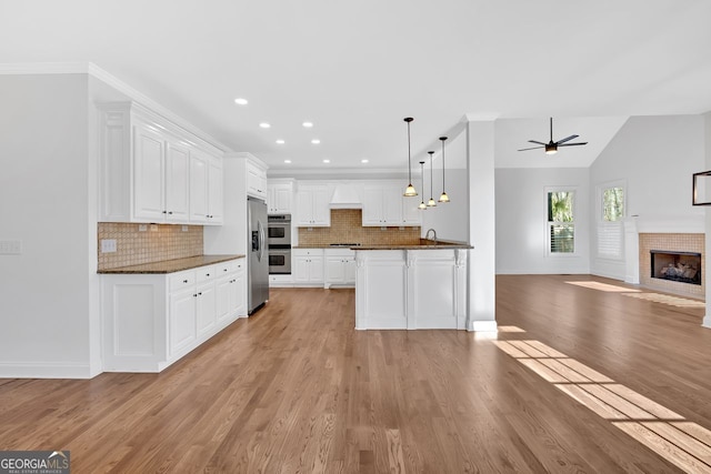 kitchen featuring a fireplace with flush hearth, light wood-style flooring, open floor plan, white cabinetry, and ceiling fan