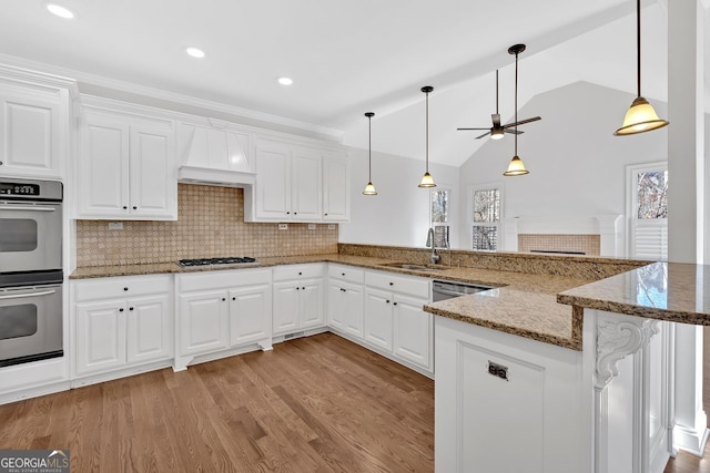 kitchen featuring premium range hood, a sink, stainless steel appliances, light wood-style floors, and a peninsula