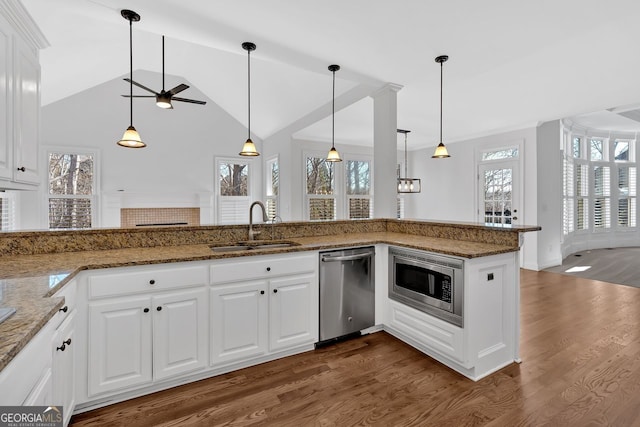 kitchen with dark wood-type flooring, a sink, appliances with stainless steel finishes, white cabinets, and stone counters