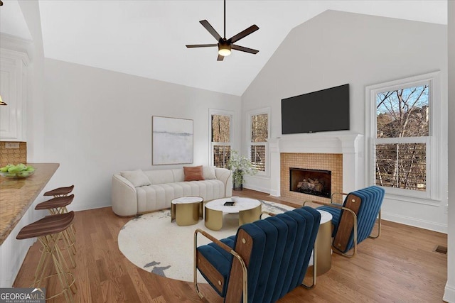 living room featuring visible vents, ceiling fan, a tile fireplace, wood finished floors, and high vaulted ceiling