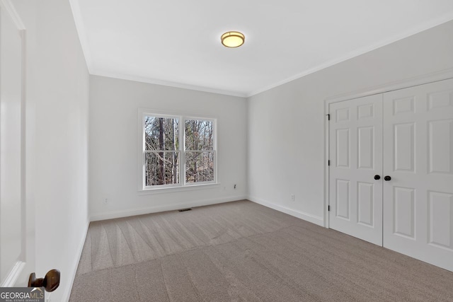 unfurnished bedroom featuring visible vents, baseboards, crown molding, and carpet