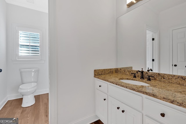 bathroom featuring baseboards, toilet, wood finished floors, and vanity