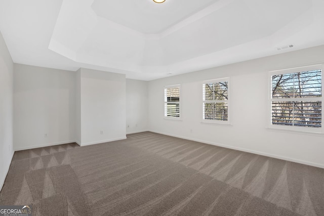 unfurnished room with a raised ceiling, baseboards, visible vents, and carpet floors