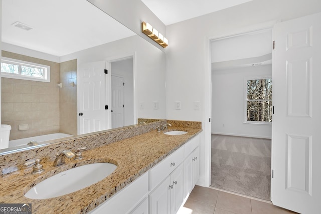 bathroom featuring a sink, visible vents, double vanity, and tile patterned floors