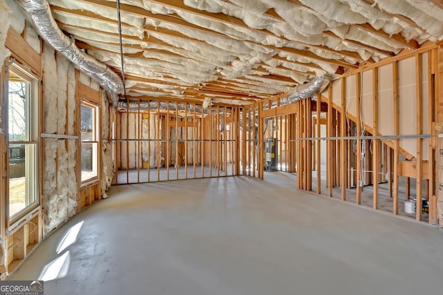 misc room with water heater, a healthy amount of sunlight, and concrete flooring