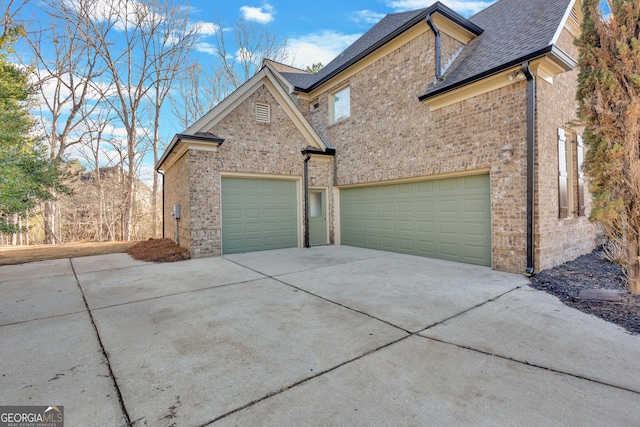 exterior space featuring brick siding, a garage, driveway, and roof with shingles