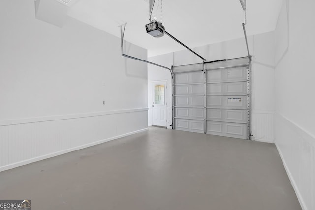 garage featuring baseboards, a garage door opener, and wainscoting