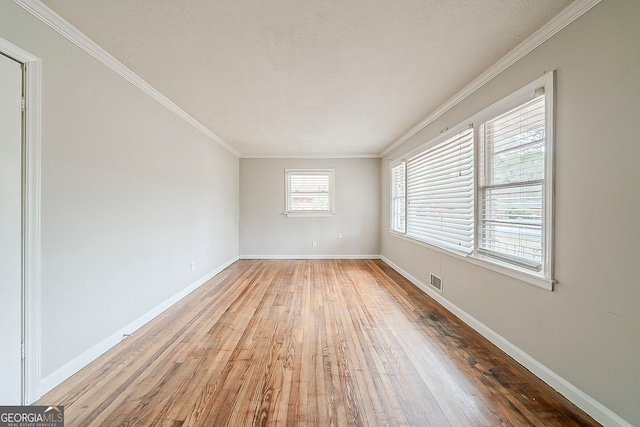 spare room featuring visible vents, crown molding, baseboards, and hardwood / wood-style floors