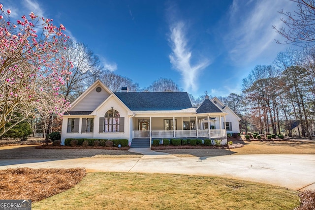 view of front of property with a chimney, covered porch, and a front yard