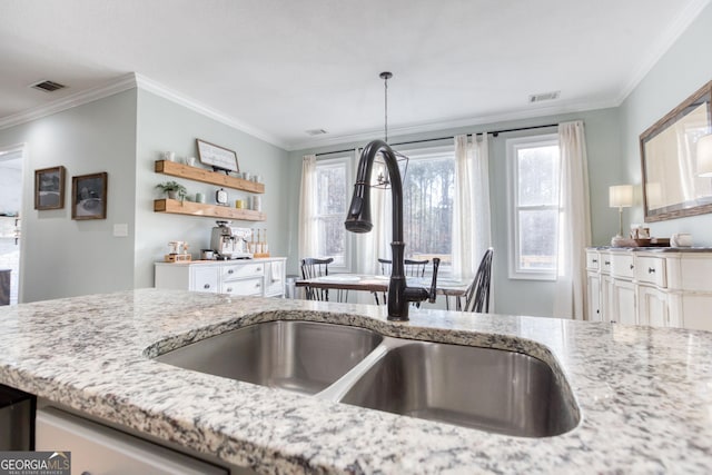 kitchen featuring ornamental molding, light stone countertops, visible vents, and a sink