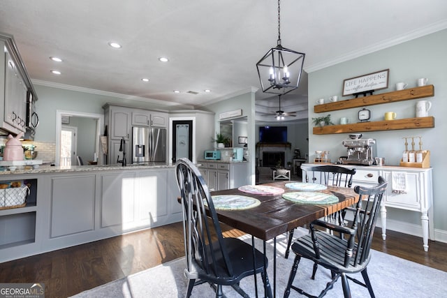 dining room featuring dark wood finished floors, ornamental molding, recessed lighting, a fireplace, and a ceiling fan