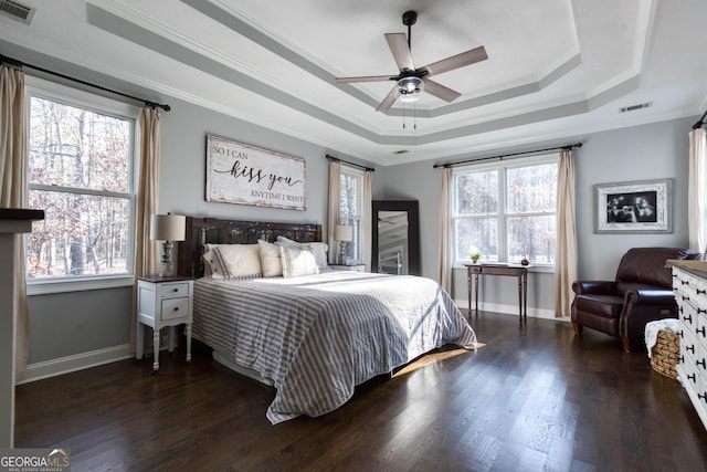 bedroom with visible vents, ornamental molding, a tray ceiling, and wood finished floors