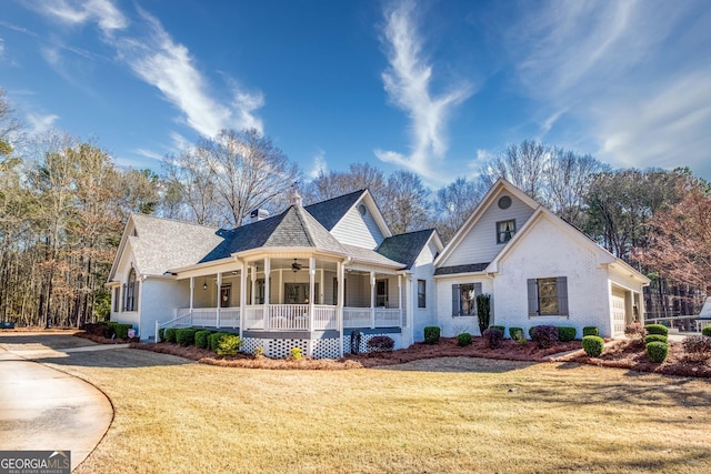 view of front facade with a ceiling fan, a front lawn, a porch, an attached garage, and brick siding