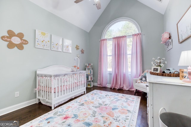 bedroom with a crib, vaulted ceiling, wood finished floors, and baseboards