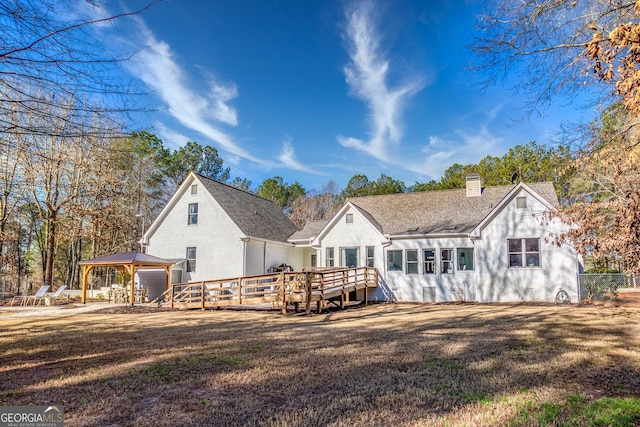 rear view of property featuring a gazebo, a wooden deck, a yard, and a chimney