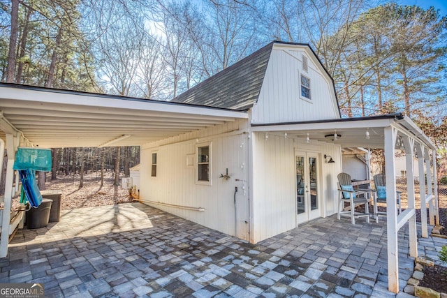 exterior space featuring french doors, a gambrel roof, and a shingled roof