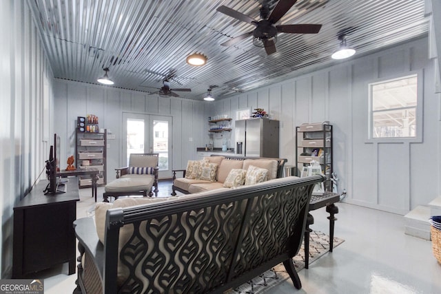 living area with a ceiling fan, french doors, and concrete floors